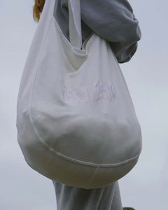 Taysia, a young woman, is wearing cropped sweatshit and pants, and holding the tote bag. 