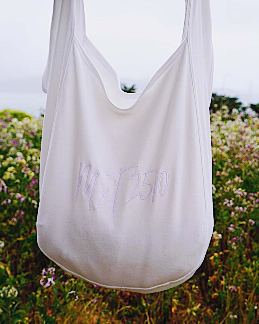 The tote features the MxT 2510 logo in white for a sleek look in front of the bush and flower.